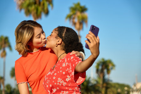 Lesbian couple kissing while taking a selfie outdoorsの写真素材