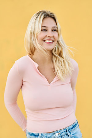 Cute blonde woman looking away standing with a yellow backgroundの写真素材