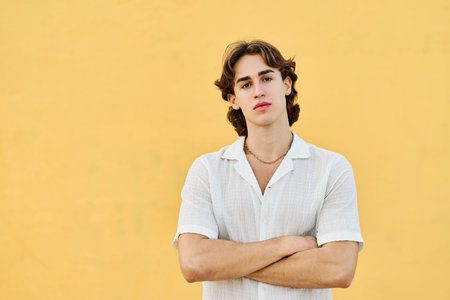 Proud young man standing serious with arms crossedの写真素材