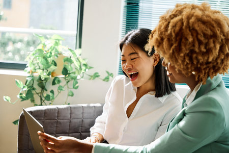 Happy asian woman using laptop whit an african colleagueの写真素材