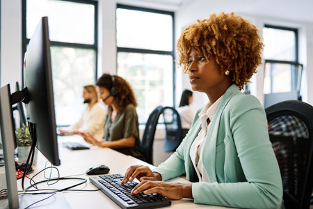 African woman using computer sitting on a coworking deskの写真素材