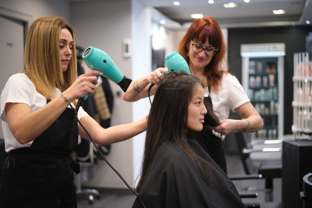 Hairdressers drying the hair of a woman at the salonの写真素材