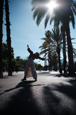 Woman dancing freely in sunny palm tree parkの写真素材