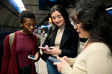 Young diverse women using smartphones in subway station