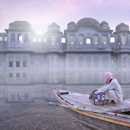 Indian man with flowers on his boat in the mist.の写真素材