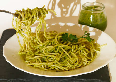 Male having a Spaghetti with pesto sauce and a parsley leaf and the image is decorated with a glass...