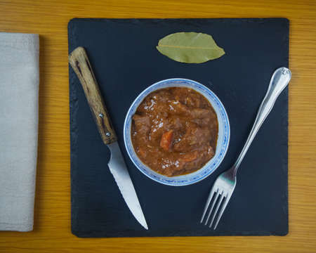 Fricando, Traditional Catalan tapa, stew of beef in a bowl decorated with metal cutlery, a napkin...