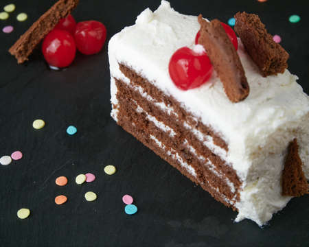 Black forest slice decorated with cherries, small pieces of cake and decorative and colorful sugar...
