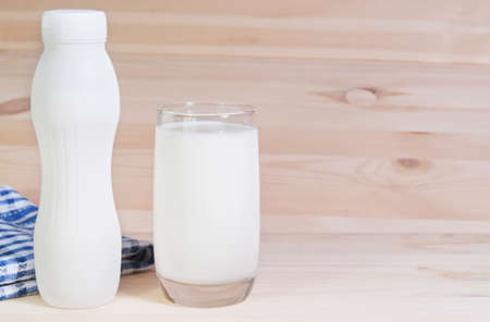 Milk in white plastic bottle and in glass on wooden backgroundの写真素材