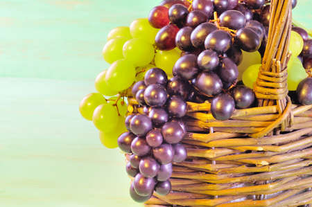 REd and green Grape bunches in basket on wooden table with copy spaceの写真素材