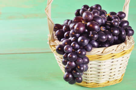 Red grape in basket on wooden table with copy spaceの写真素材