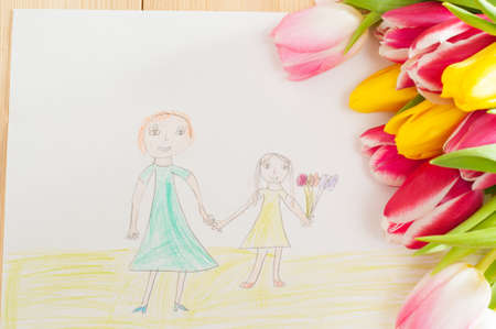 Bouquet of tulips and kids picture with mother and daugther on the wooden backgroundの写真素材