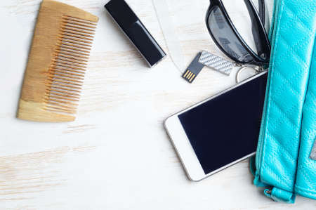 Woman's bag and it's content - phone, lipstick, sunglasses, nail file, USB flash drive, combの写真素材
