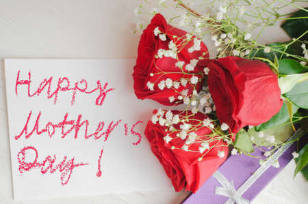 Three roses, greeting card for mother and purple gift box on wooden backgroundの写真素材