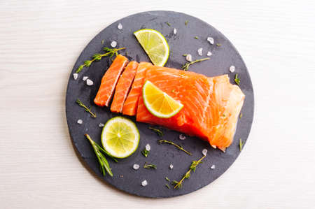 Fresh trout piece with herbs and lime on slate boardの写真素材