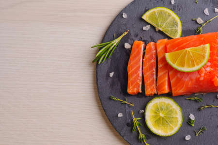 Fresh trout piece with herbs and lime on slate boardの写真素材