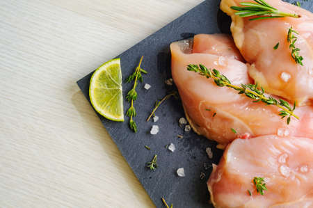 Fresh chicken fillet breast with herbs and the lime on slate board