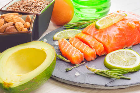 Omega 3 sources - piece of fish, avocado, nuts, linen seeds and eggの写真素材