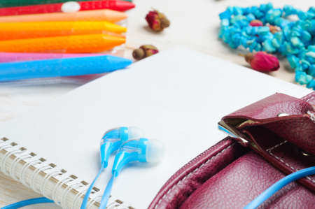 Earphones on the blank page of notebook and pencils