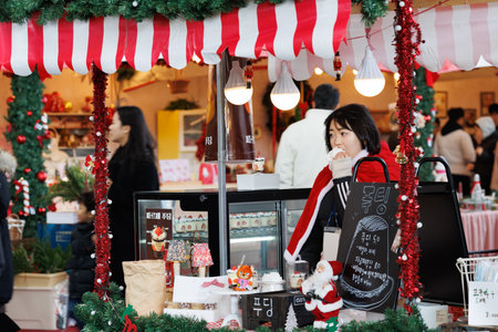 Busan, South Korea, 16 December 2025 Christmas market set in a holiday village with decorated wooden stalls and seasonal goods. People walking among the stands create a lively winter holiday atmosphere in an urban environmentのeditorial素材