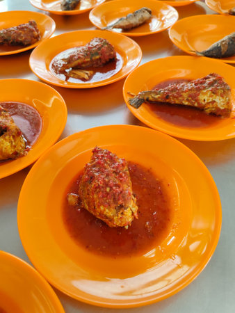 Fried fish with spicy sauce in orange dish on the table.の写真素材