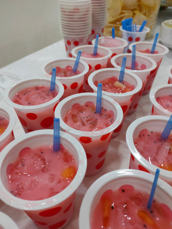 Watermelon smoothies in plastic cups with straws on the tableの写真素材