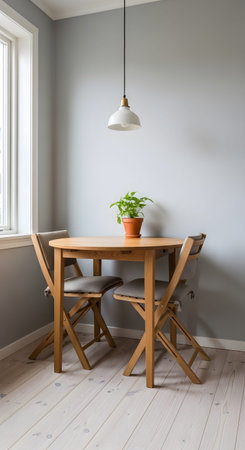 A small round wooden table with two chairs sits in a minimalist room with grey walls and a window.