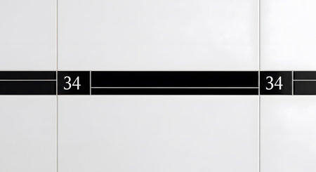 Toilet showing close-up of white wall tiles with a black horizontal stripe and the number 34...の写真素材