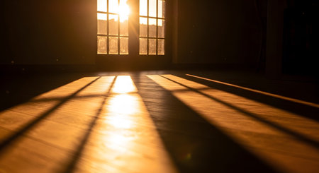 Warm golden sunlight streams through a window, casting striped shadows across a wooden floor...