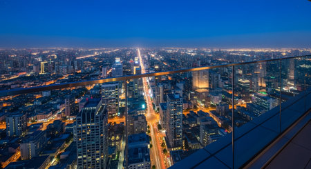 A vast cityscape stretches to the horizon under a deep blue twilight sky with glowing city lights.