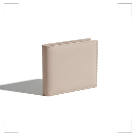 A minimalist beige leather bifold wallet with subtle stitching is positioned on a white surface...