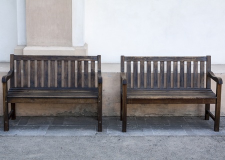 Two empty wooden benches with wall on the backgroundの写真素材