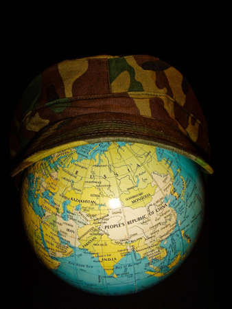 Military cap on a globe, showing military powerの写真素材