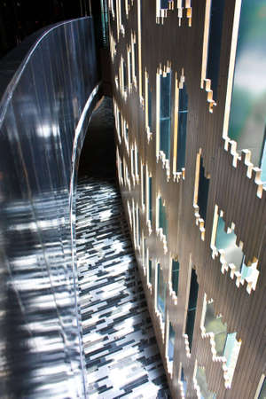 The interior of a artisitic building with reflective marble flooring and unique wooden wall
