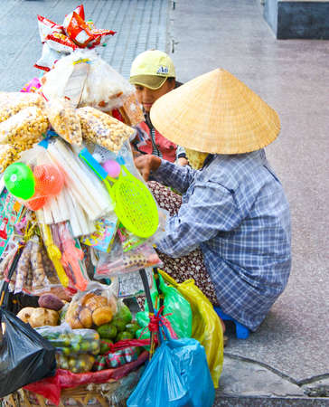 Ho Chi Minh City, Vietnam - June 10, 2010 - A Vietnamese lady sells various items along the sidewalk.のeditorial素材