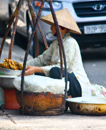 Ho Chi Minh City, Vietnam - June 10, 2010 - A Vietnamese lady squats by the road side and selling food to the public.のeditorial素材