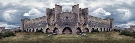 Mighty medieval city wall defences in panorama with dramatic colors and sky のeditorial素材