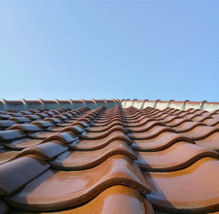 Wavy pattern of brown ceramic rooftop tile. Light source is come from direct sunlight