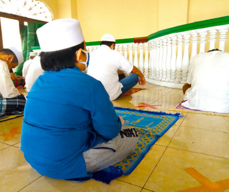 A boy wear mask is listening to friday prayer sermon. A friday prayer that apply social distancing and health protocol covid in Indonesia, Masjid Al-Muttaqinのeditorial素材