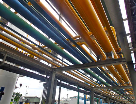 Line of oil processing piping systems in oil fields. Different colors mean different fluids; yellow for gas; green for oil; blue for water; white for compressed airの写真素材
