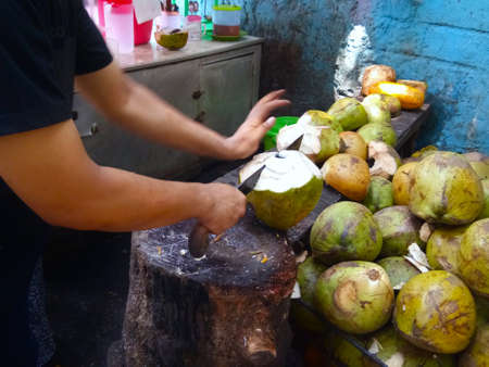 A man split a coconut in a half. The picture was taken during the afternoon on the coconut stallの写真素材