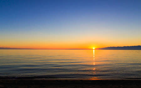 Sunset on the lake. Beautiful low sun, calm water. A beautiful summer evening in nature.の写真素材
