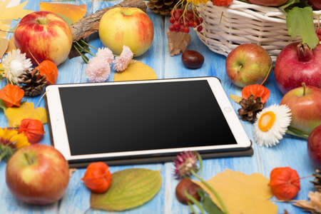 The tablet. Autumn bright background. Flowers, leaves and fruits on a blue wooden background. Background for the autumn holidays and thanksgiving day.の写真素材