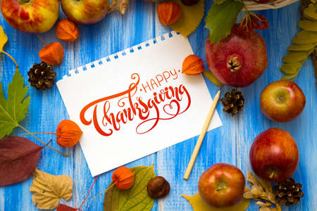 Thanksgiving - letters. Autumn bright background. Flowers, leaves and fruits on a blue wooden background. Background for the autumn holidays and thanksgiving day.の写真素材