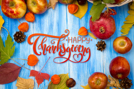 Thanksgiving - letters. Autumn bright background. Flowers, leaves and fruits on a blue wooden background. Background for the autumn holidays and thanksgiving day.の写真素材