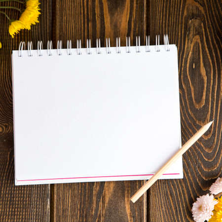 Autumn bright background. Notebook for the inscription. Flowers, leaves and fruits on a brown wooden background. Background for the autumn holidays and thanksgiving day.の写真素材
