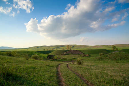 Beautiful spring and summer landscape. Lush green hills, high snowy mountains. Country road....