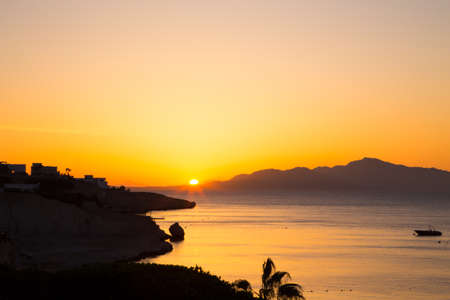 Sunrise over the red sea. Beautiful bright sky with sun rays and morning clouds. Sea and boats. View of Tiran Island. Egypt, Sharm El Sheikh. Tourism and travel. Rest and vacation.の写真素材