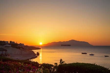 Sunrise over the red sea. Beautiful bright sky with sun rays and morning clouds. Sea and boats. View of Tiran Island. Egypt, Sharm El Sheikh. Tourism and travel. Rest and vacation.の写真素材