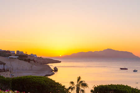 Sunrise over the red sea. Beautiful bright sky with sun rays and morning clouds. Sea and boats. View of Tiran Island. Egypt, Sharm El Sheikh. Tourism and travel. Rest and vacation.の写真素材